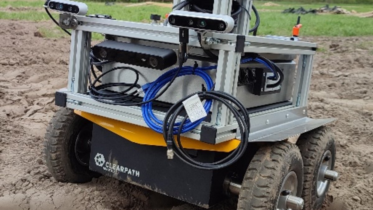 Ein kleiner Feldroboter mit Sensorsystem steht auf einem Acker