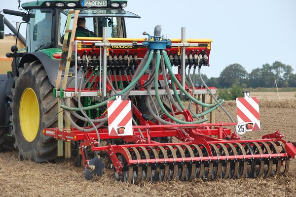 Ein Traktor fährt mit einer Sämaschine auf einem Acker.