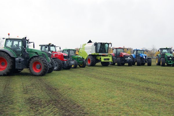 Eine Vielzahl von Landmaschinen steht in einer Reihe auf einem Feld.